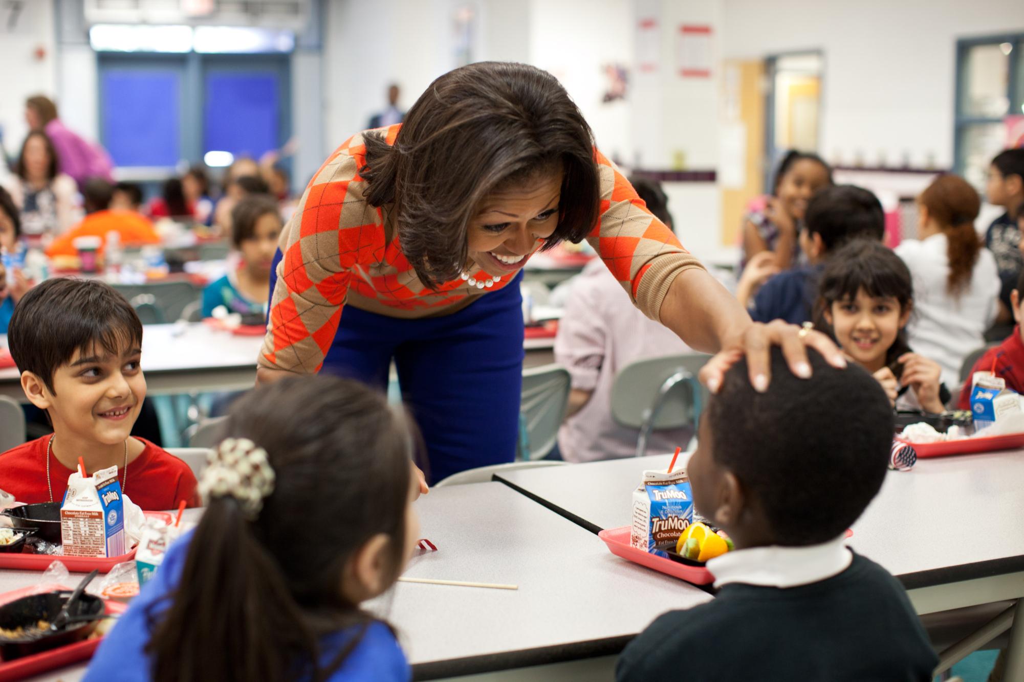 Michelle Obama interacts with students during a school lunch. Promoting healthy eating habits to kids.