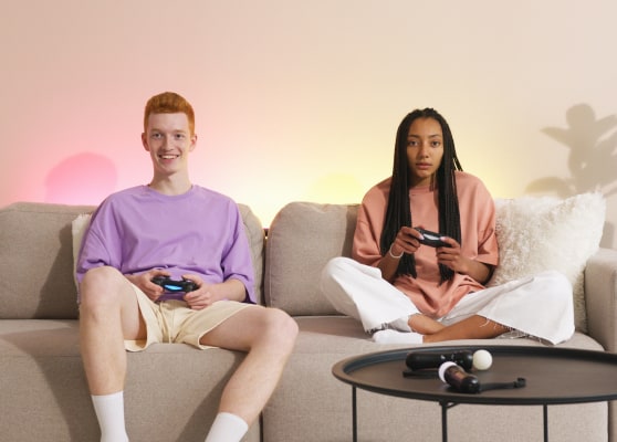 Two friends playing video games on a couch, smiling and focused.
