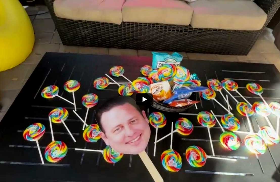 Table with lollipops, snacks, and a cutout of a man's face. Celebrating the Candy Hall of Fame.