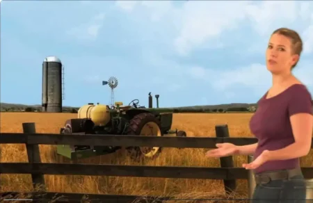 Woman on a farm with a tractor, silo, and windmill. Saving Small Farms.