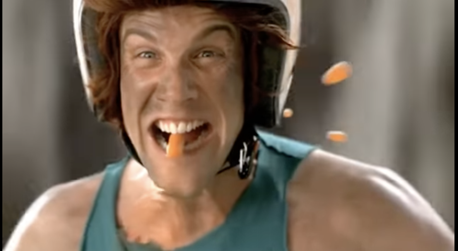 Man in helmet eating carrot, promoting healthy foods.