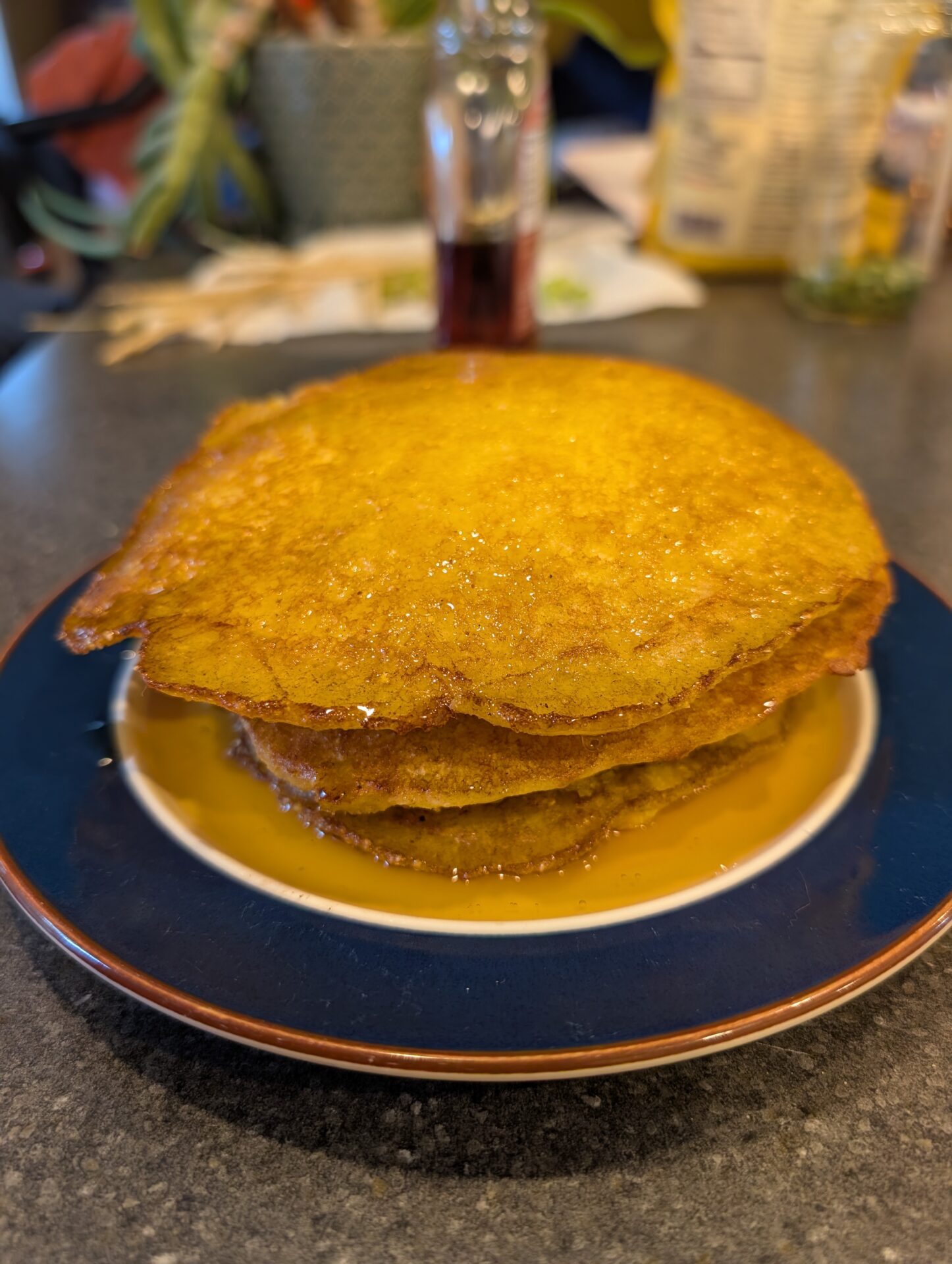 Stack of golden pancakes drizzled with syrup on a blue plate
