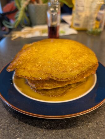 Stack of golden pancakes drizzled with syrup on a blue plate