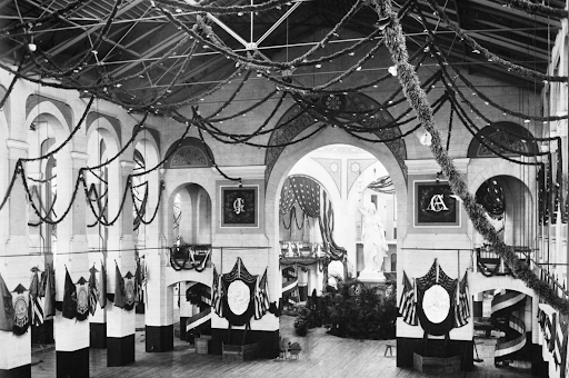 Interior of a hall decorated with flags and garlands, possibly honoring James A. Garfield.