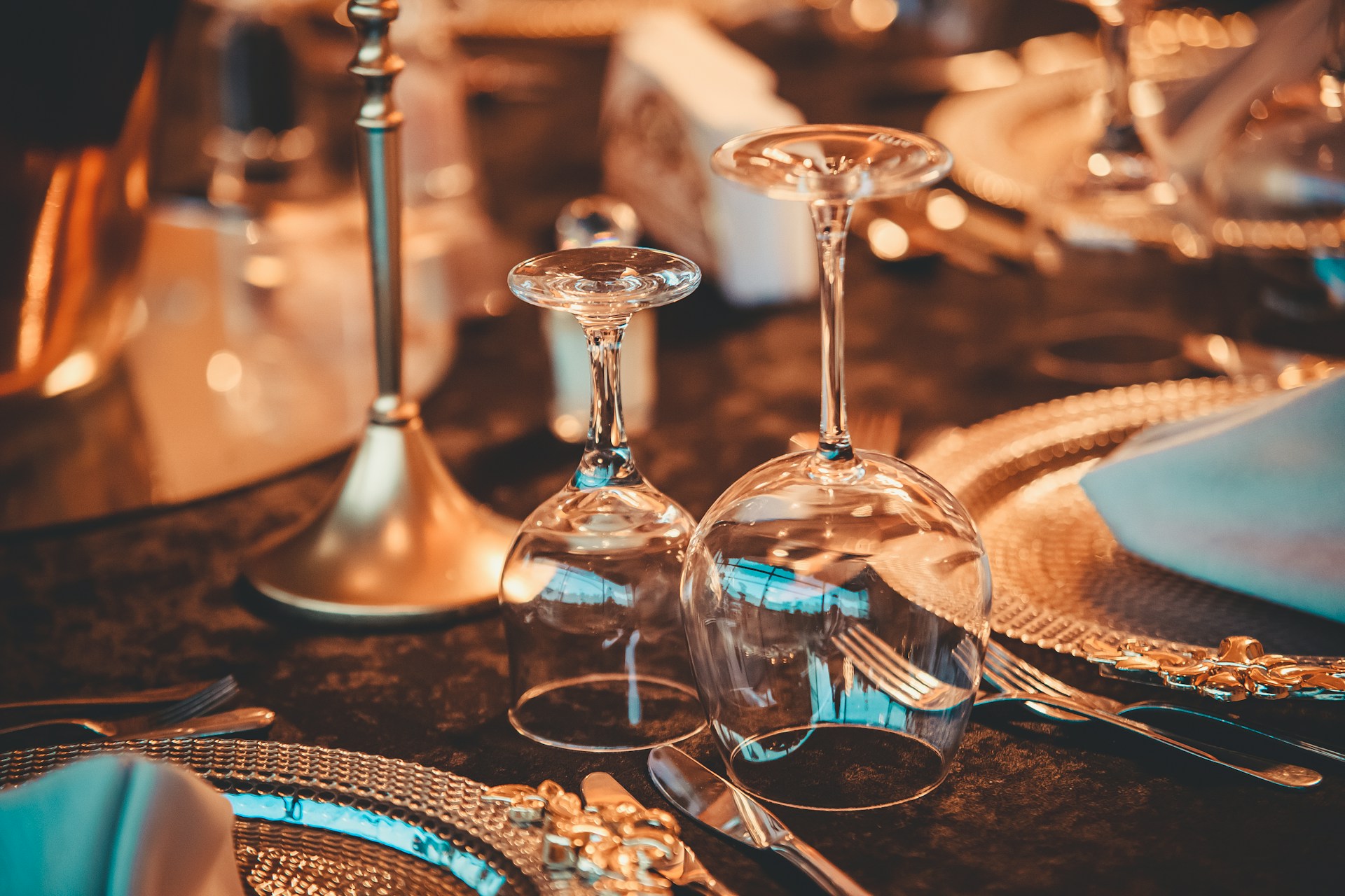 Elegant table setting with ornate chargers, silverware, and wine glasses.