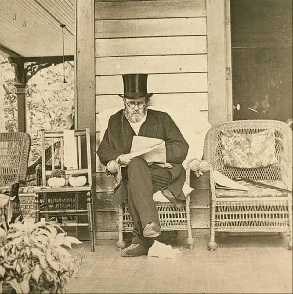 Ulysses S. Grant sits reading a newspaper on a porch.