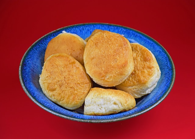 A blue bowl filled with golden brown biscuits on a red background.