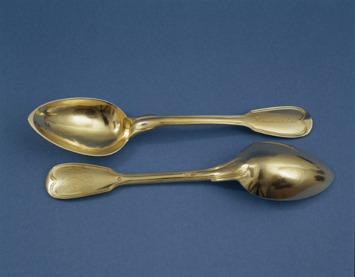 Two ornate silver spoons, one inscribed "Edmund L. Ross," on a blue background.
