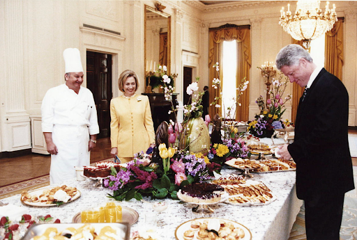 Bill Clinton, Hillary Clinton, and a chef stand by a dessert buffet in the White House.