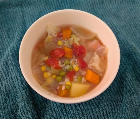 Bowl of hearty vegetable soup with rice and peas