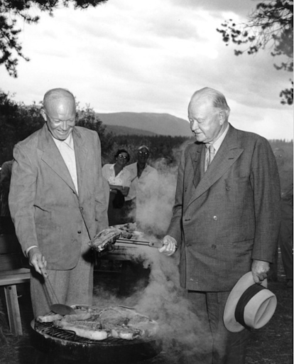 Dwight D. Eisenhower grilling outdoors with another man.