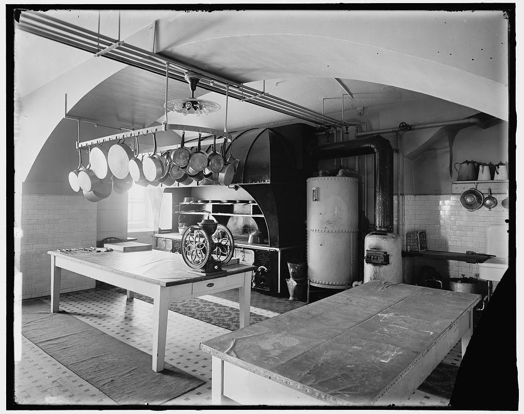 Historic kitchen with large tables, pots, and a stove