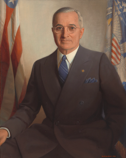Formal portrait of Harry S. Truman in a suit, with American flags