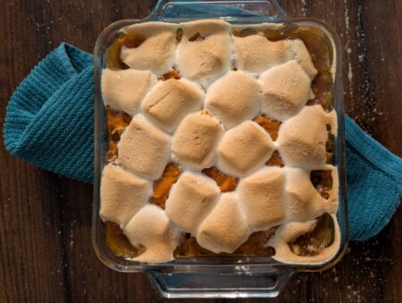 Sweet potato casserole with toasted marshmallows in a glass dish.