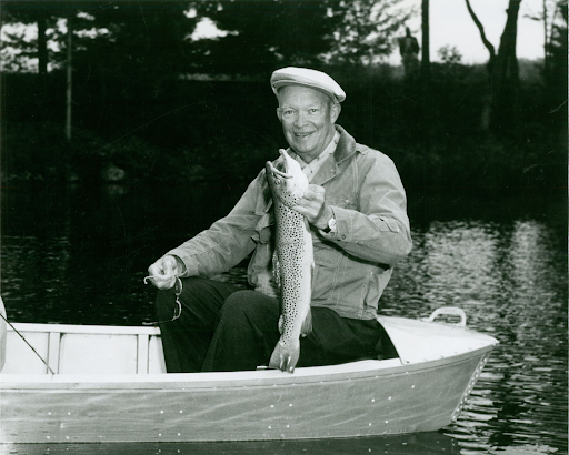 Dwight D. Eisenhower in a boat holding a large trout he caught.