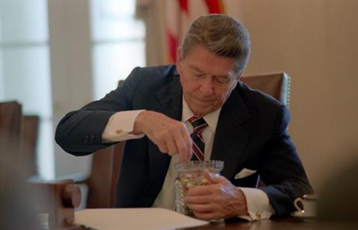 Ronald Reagan selects jelly beans from a jar in the Oval Office.