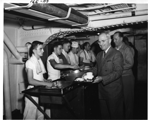 President Harry S. Truman serves food to sailors on a ship.