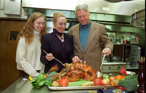 Bill Clinton and family carve Thanksgiving turkey in kitchen