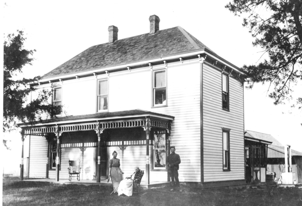 Harry S. Truman's childhood home with two figures on the porch.