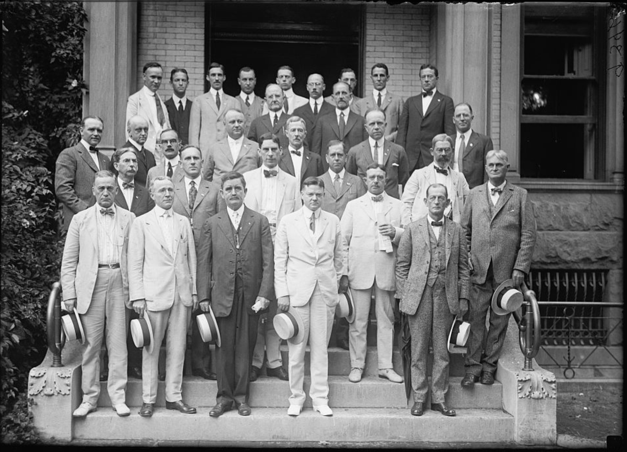 Herbert Hoover and group of men in suits posing on steps.