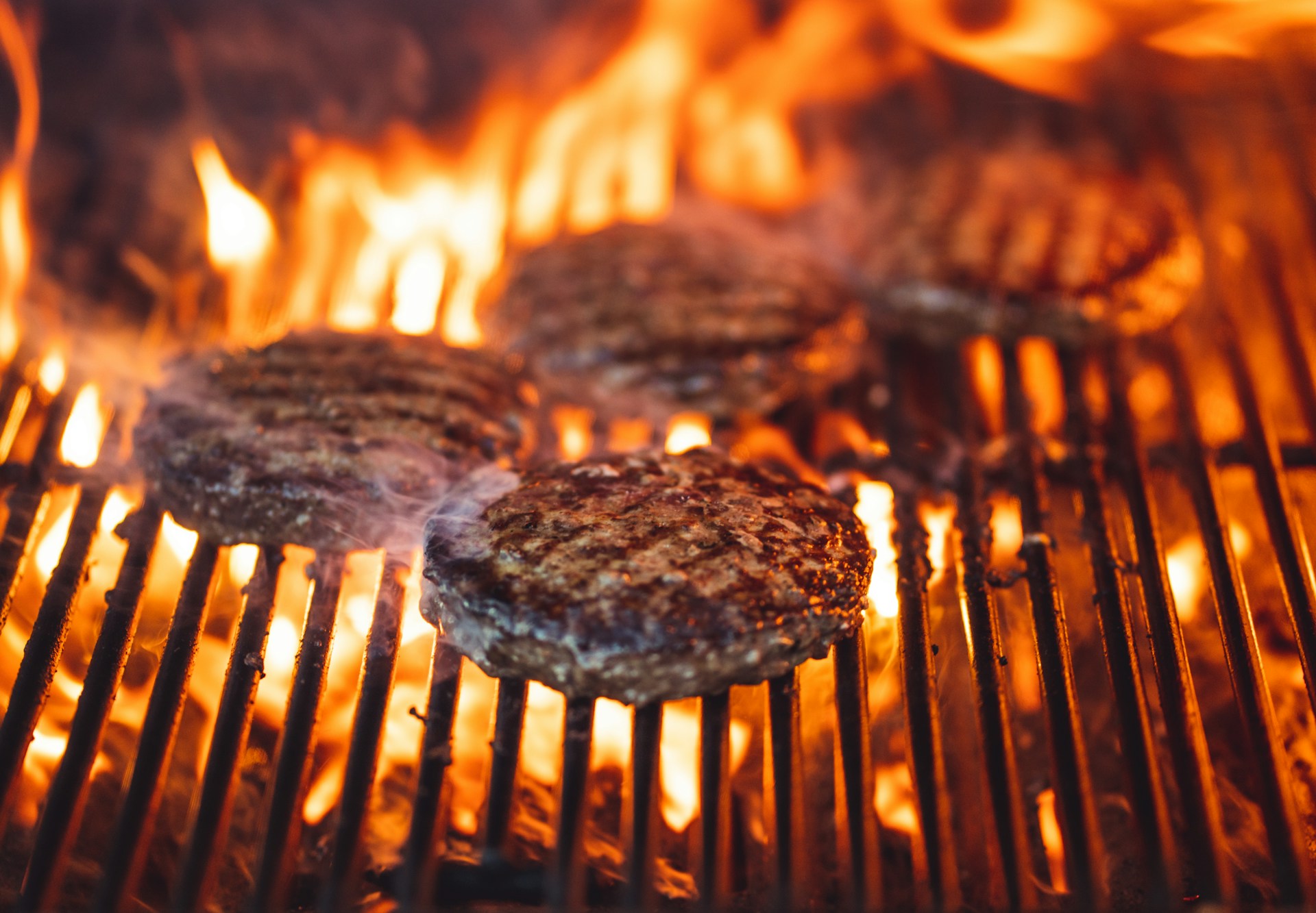 Burgers grilling over hot coals on a barbecue